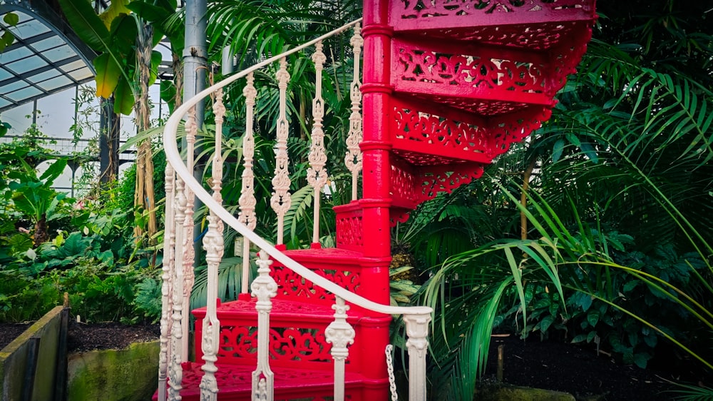 a red spiral staircase in a tropical garden