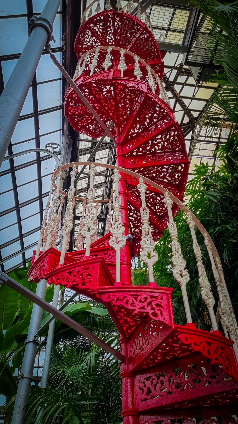 a red spiral staircase in a greenhouse
