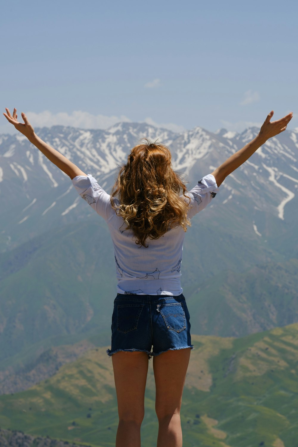 a woman standing on top of a mountain with her arms outstretched