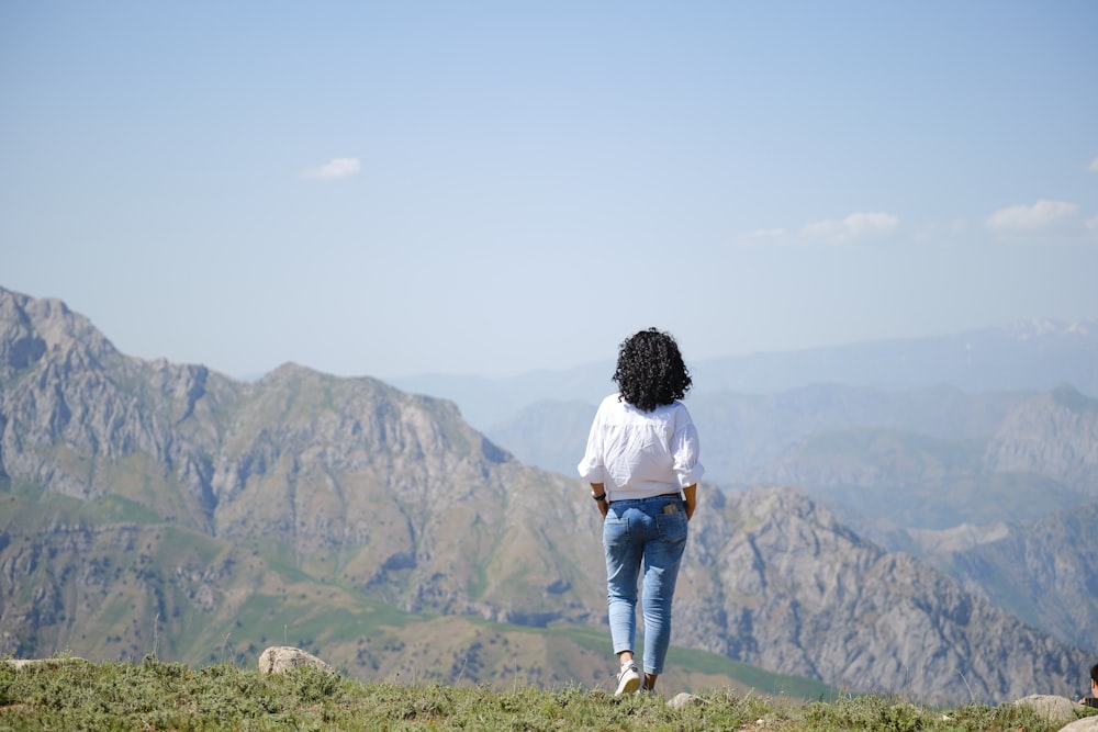 Una donna in piedi sulla cima di una collina verde lussureggiante