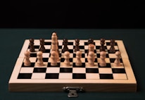 a wooden chess board with black and white pieces