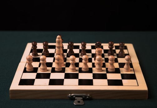 a wooden chess board with black and white pieces