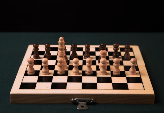 a wooden chess board with black and white pieces