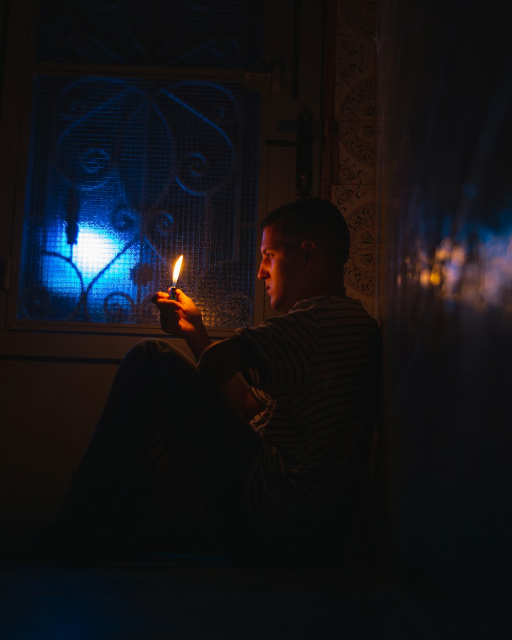 a man sitting in a dark room holding a lit candle