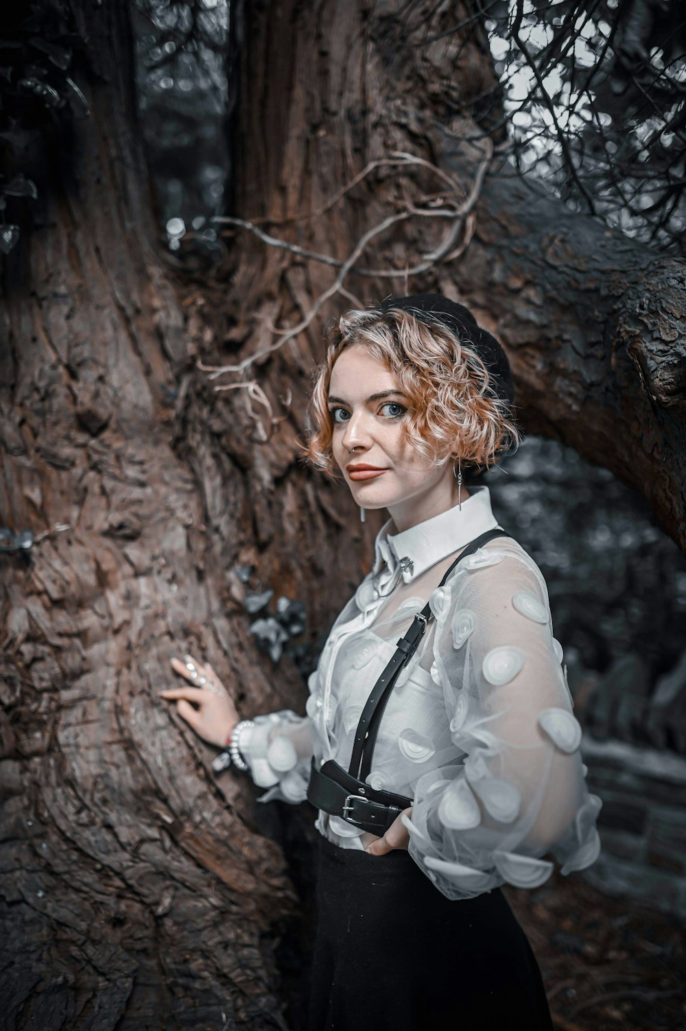 a woman standing next to a tree in a forest