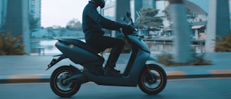 man in black jacket riding on black motor scooter during daytime