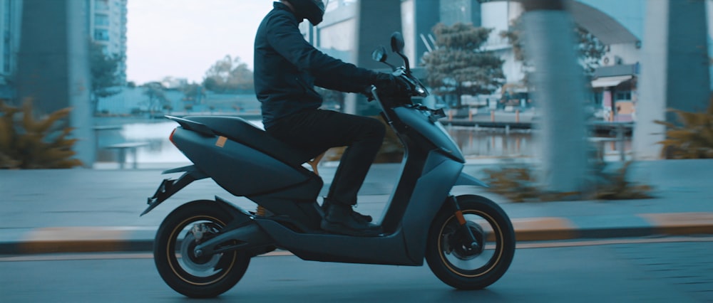 man in black jacket riding on black motor scooter during daytime