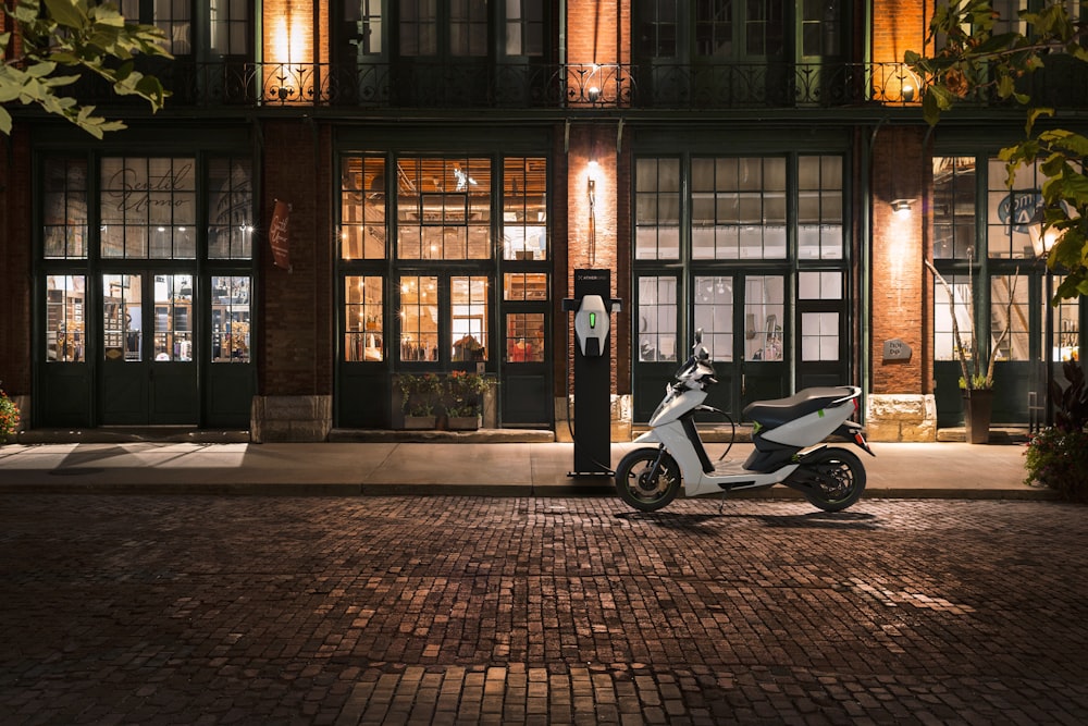 Scooter blanco y negro estacionado al lado de un edificio marrón