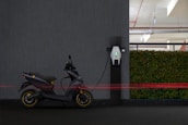 black and red motorcycle parked beside gray wall