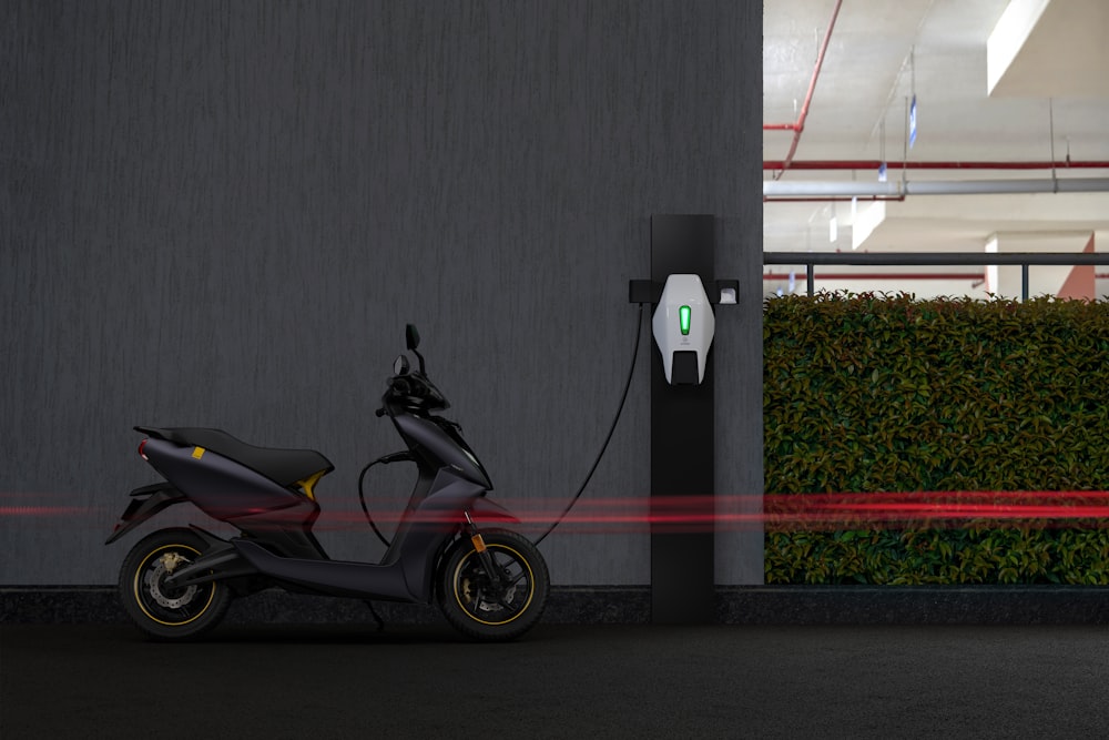 Motocicleta negra y roja estacionada junto a una pared gris