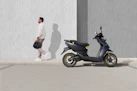 man in white t-shirt and black shorts riding blue motor scooter