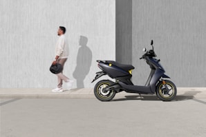 man in white t-shirt and black shorts riding blue motor scooter