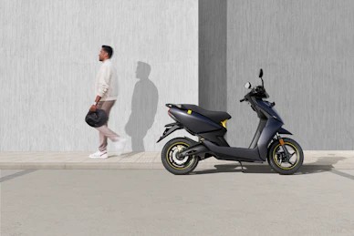 man in white t-shirt and black shorts riding blue motor scooter