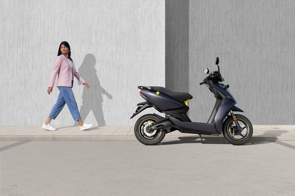 woman in pink jacket and blue denim jeans standing beside black and blue  motor scooter photo – Free Image on Unsplash