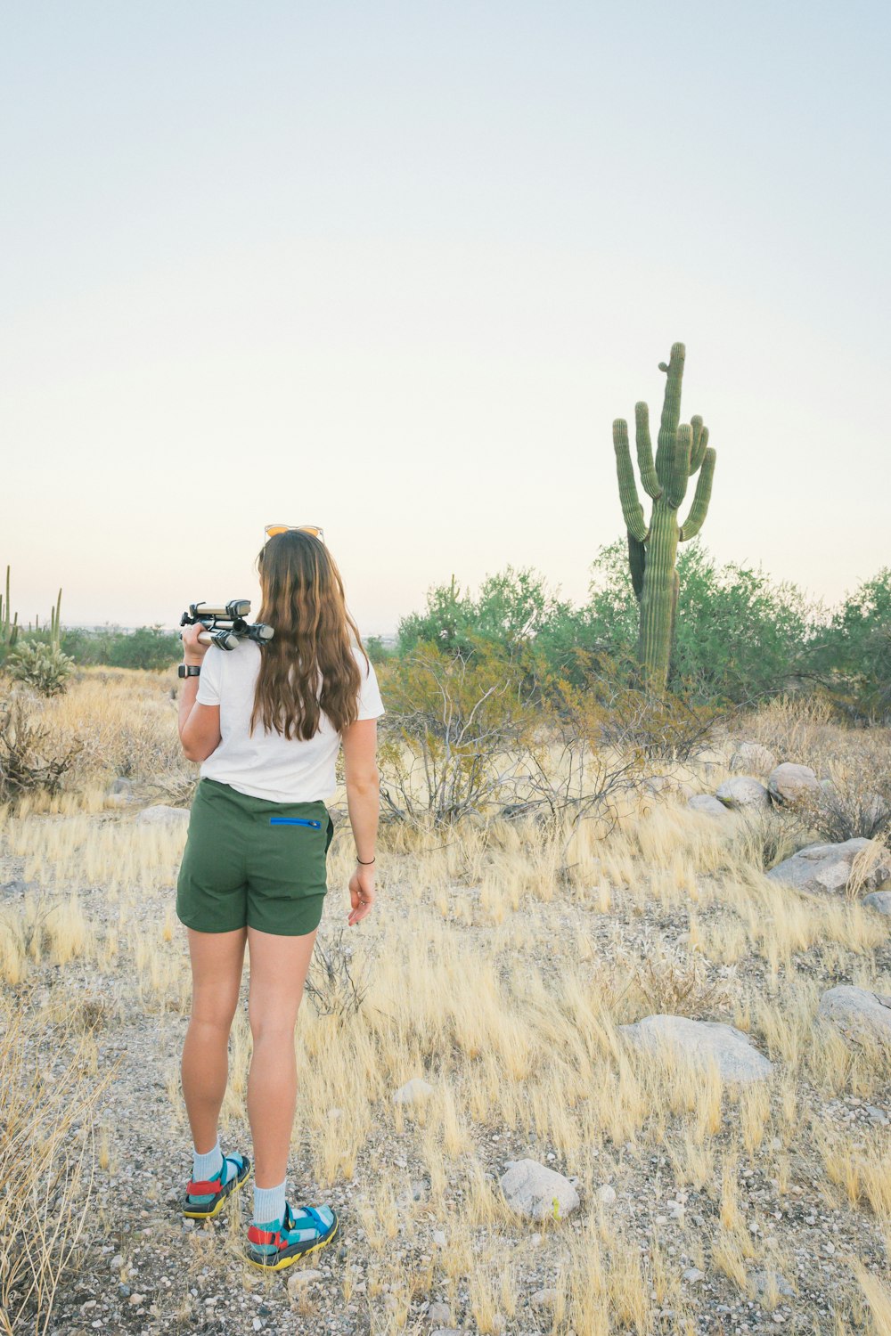 woman in white tank top and blue denim shorts standing on green grass field during daytime