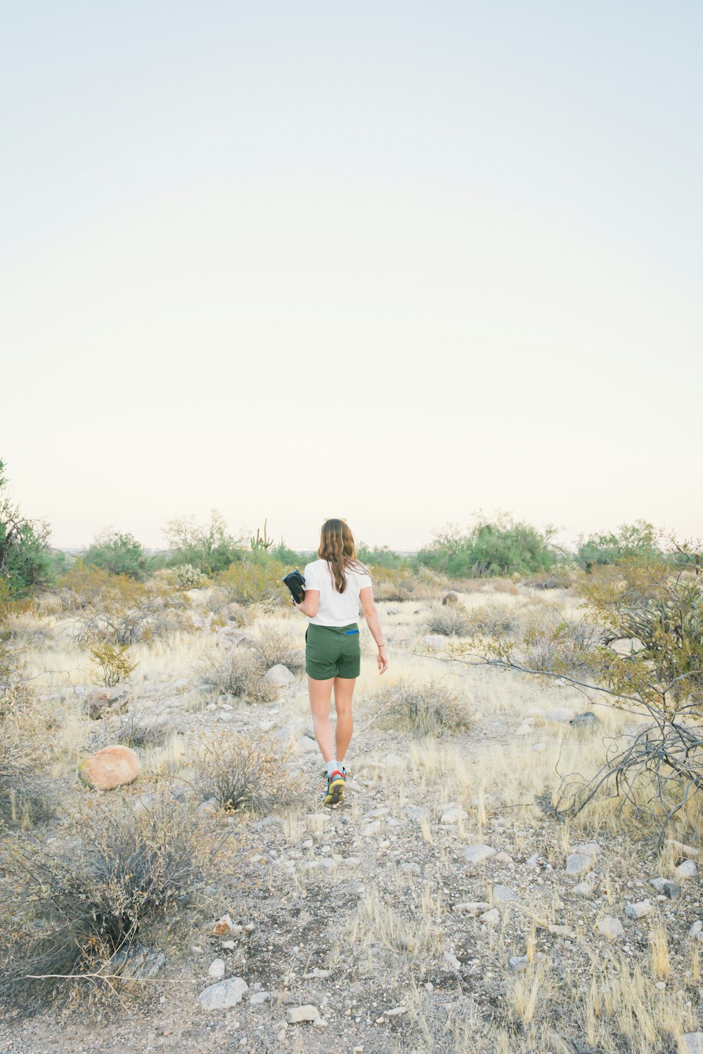 woman in black tank top and white shorts walking on dirt road during daytime