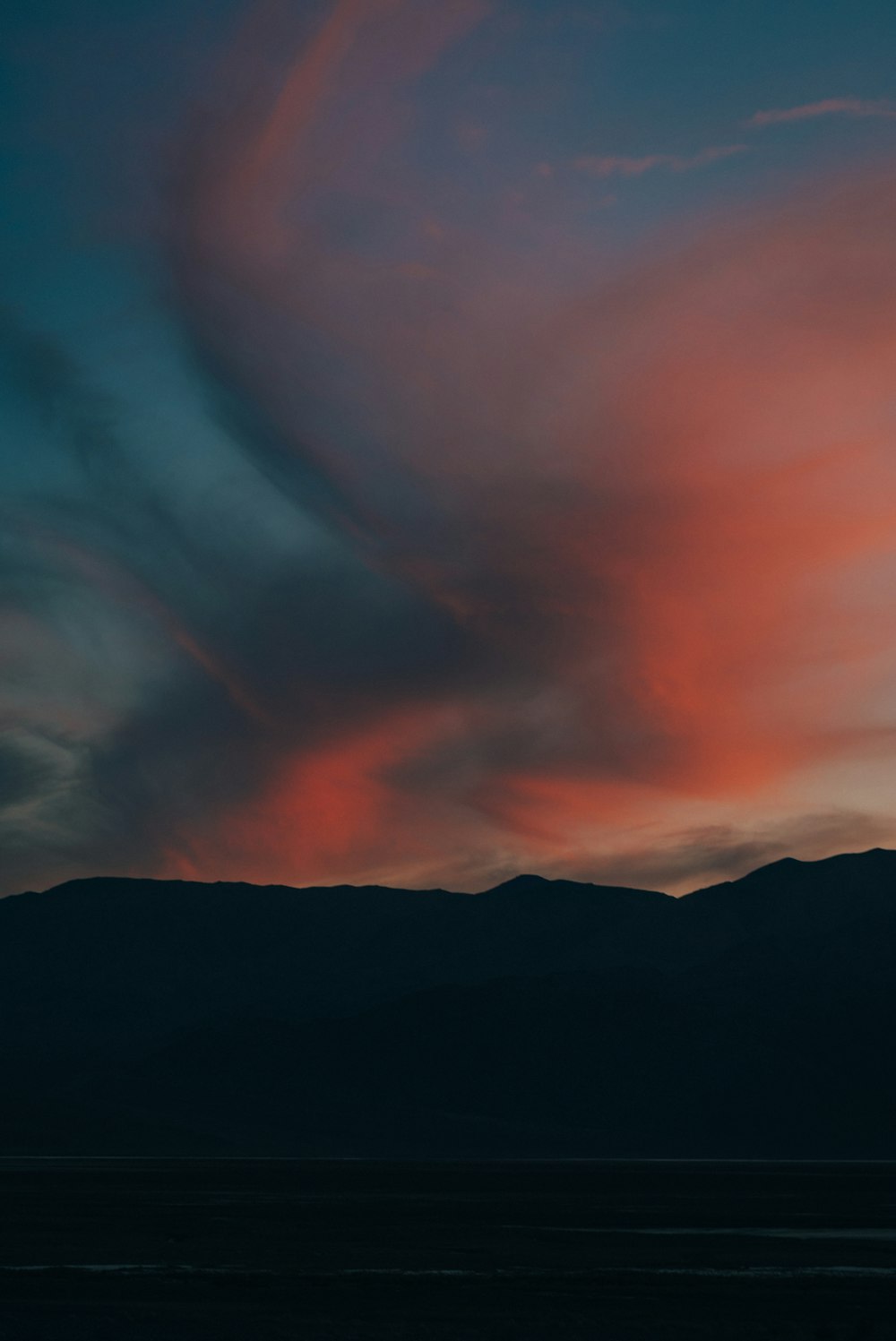 silhouette of mountain under cloudy sky during sunset