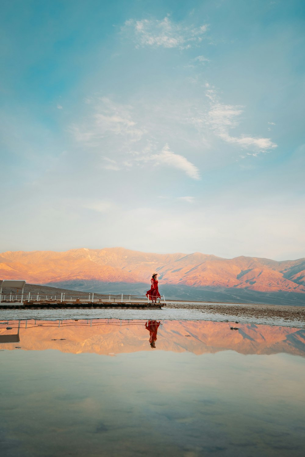 person in red jacket standing on brown sand near body of water during daytime