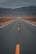black asphalt road in the middle of brown field during daytime