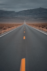 black asphalt road in the middle of brown field during daytime