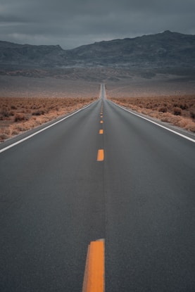 black asphalt road in the middle of brown field during daytime