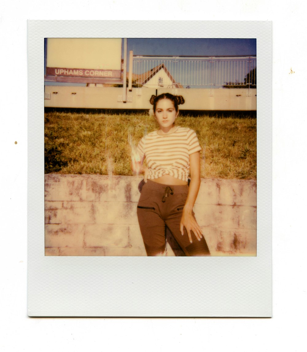 woman in white and black stripe shirt and gray pants standing on green grass field during