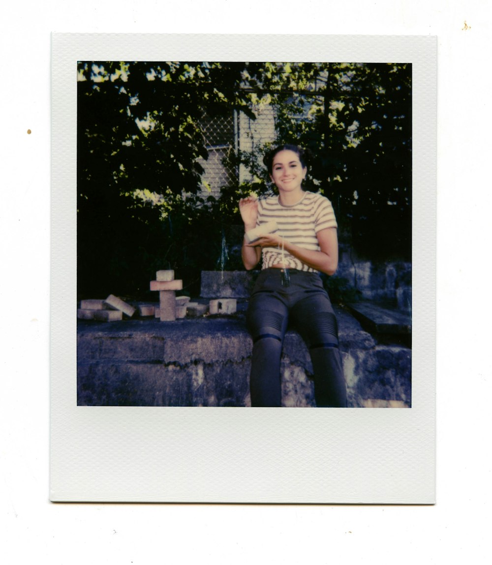 灰色のコンクリートのベンチに座っている黒と白の縞模様のシャツと青いデニムジーンズの男性