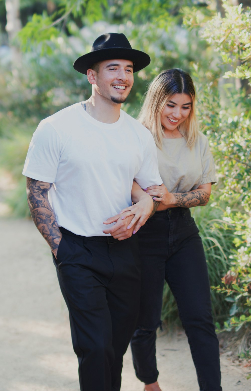 man in white crew neck t-shirt and black pants smiling beside woman in white crew