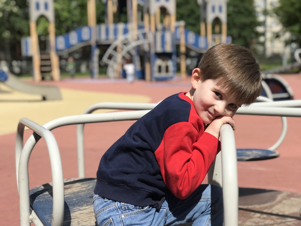 a young boy sitting on top of a metal bench