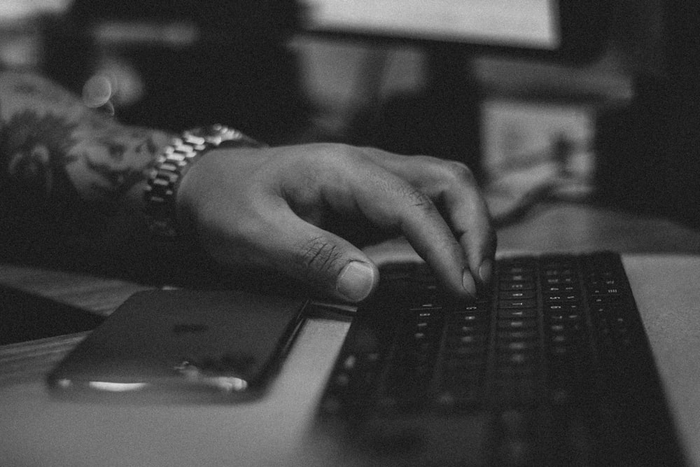 grayscale photo of persons hand on laptop computer