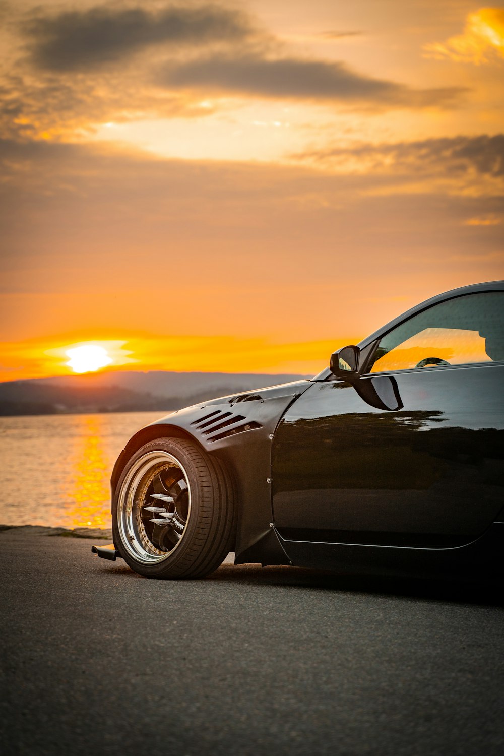Porsche 911 noire sur la route au coucher du soleil