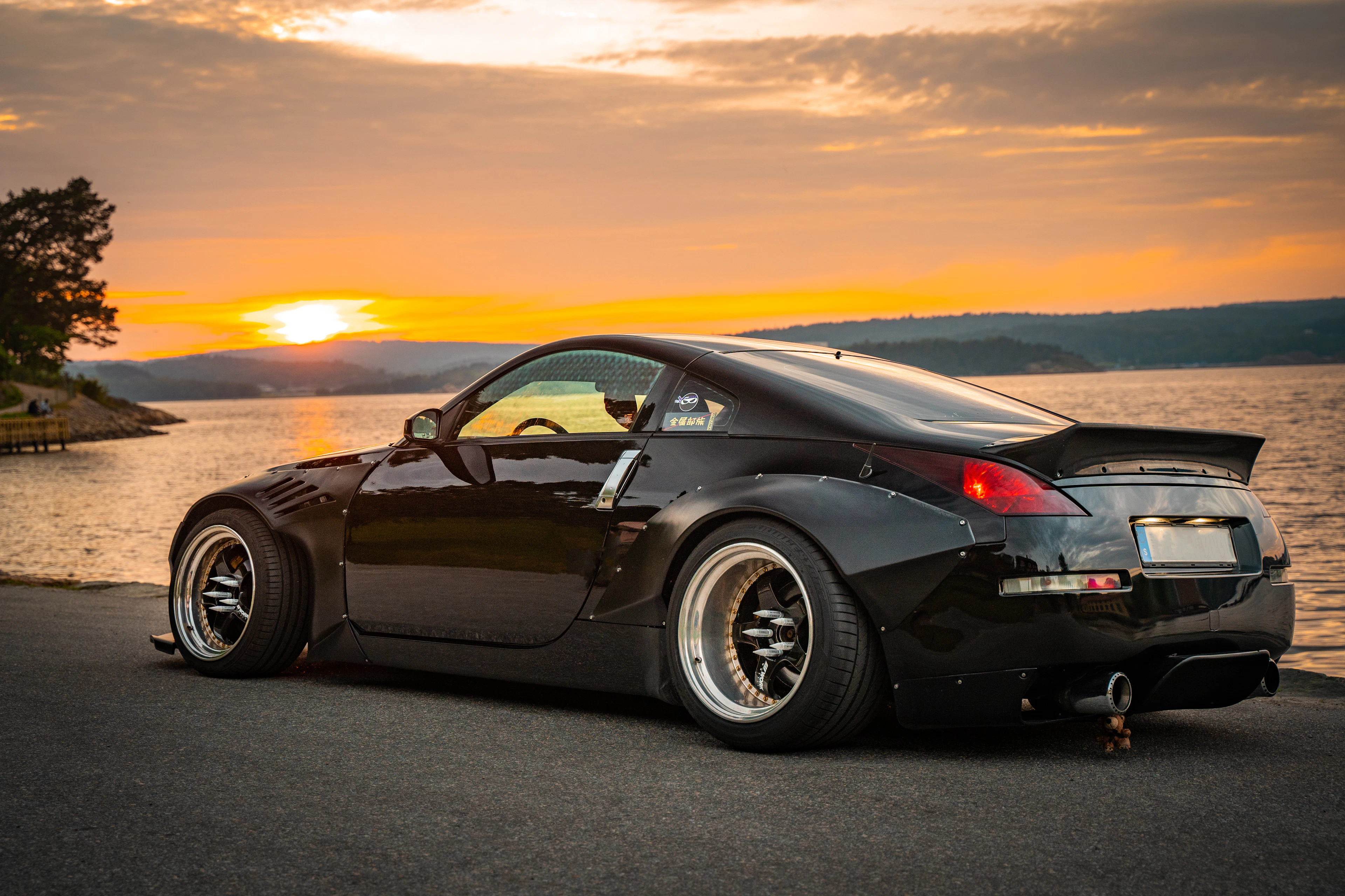 Black widebody Nissan 350Z by a lake at sunset