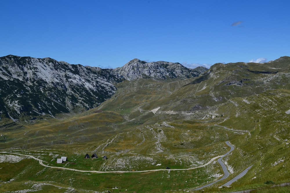 Campo di erba verde e montagne sotto il cielo blu durante il giorno