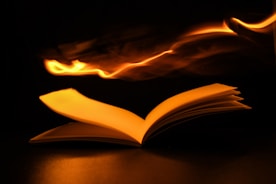Close-up of an open book with a glowing magical symbol on the page.
