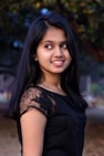 a girl in a black dress posing for a picture