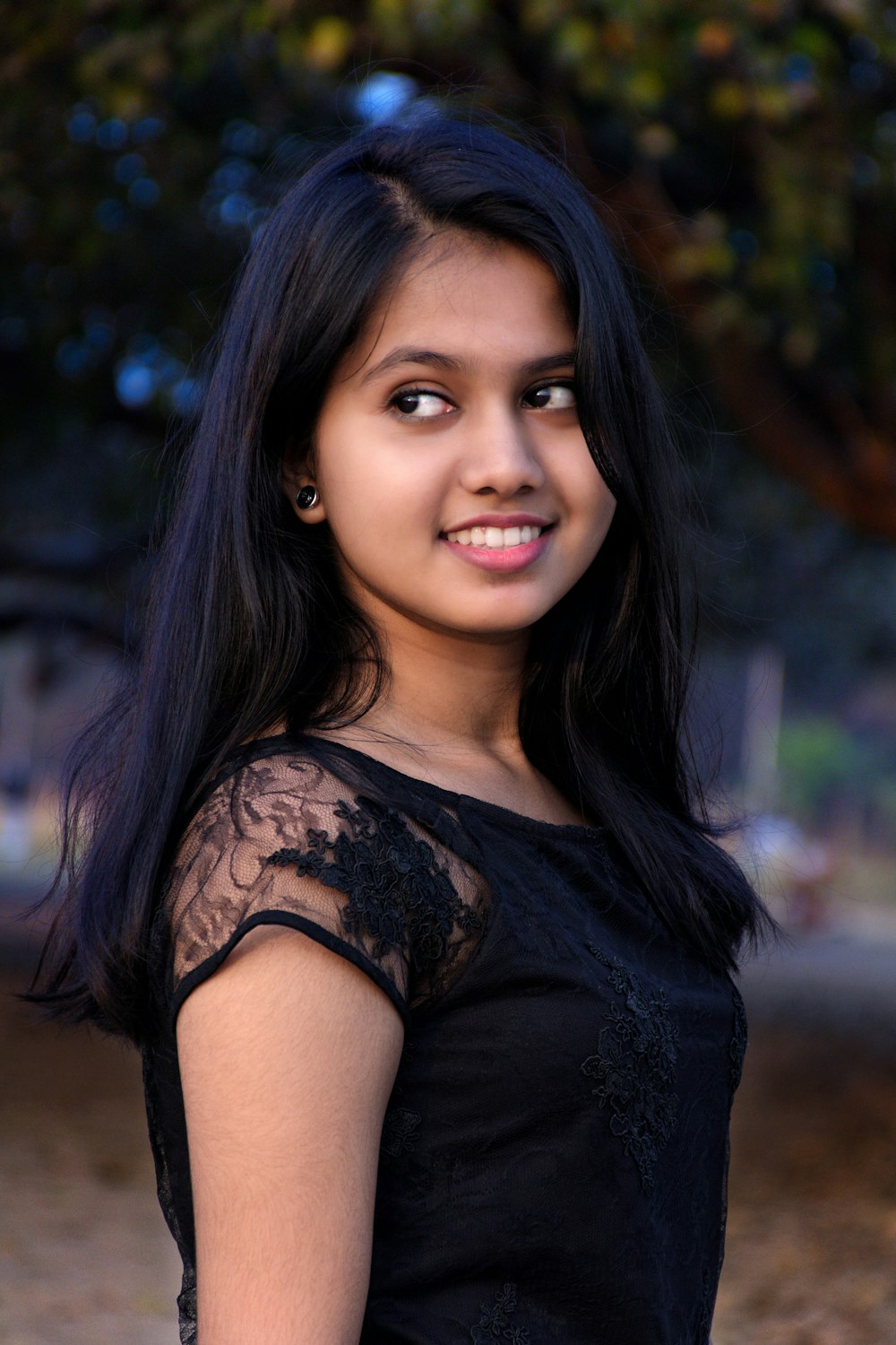 a girl in a black dress posing for a picture