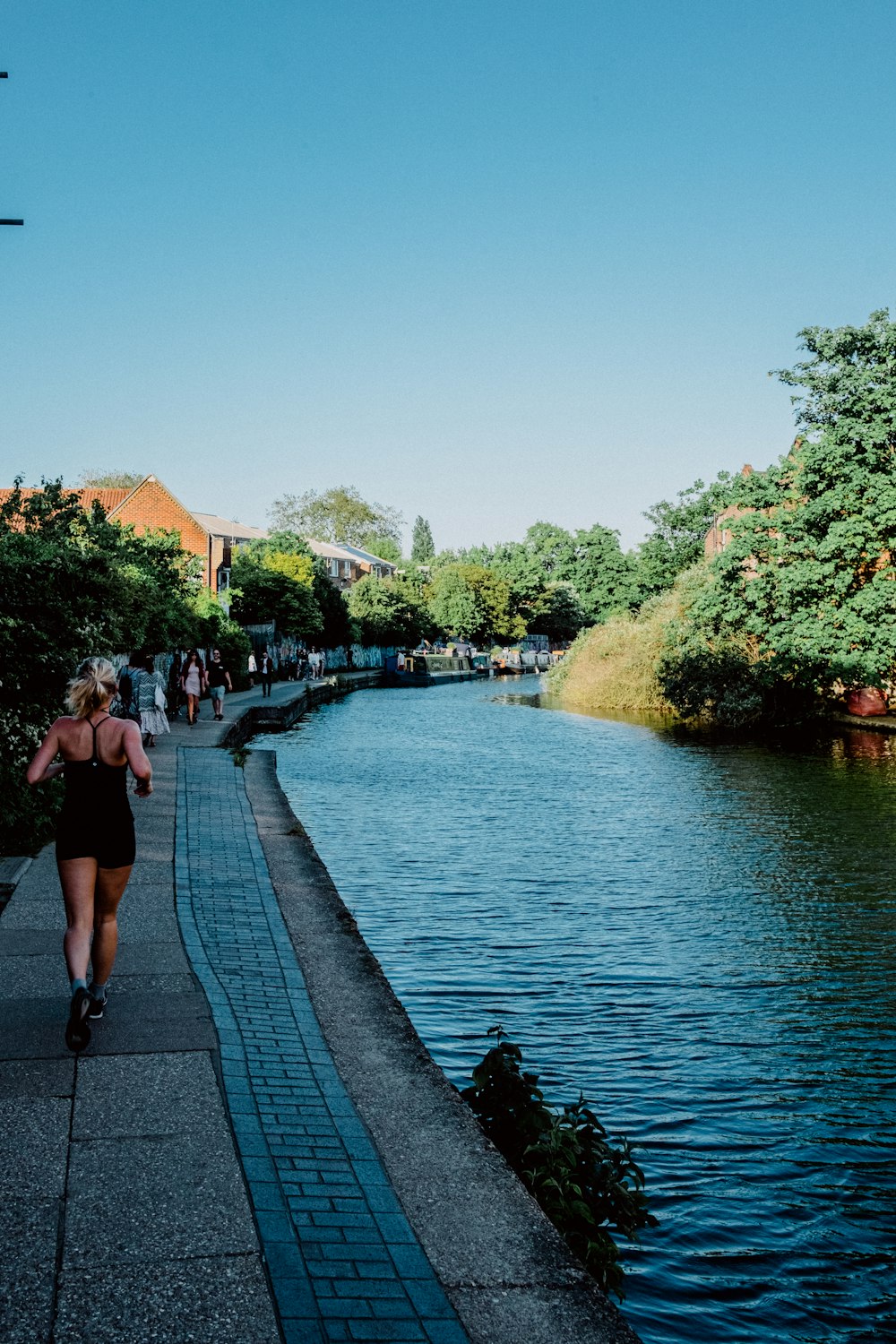 people walking on sidewalk near river during daytime