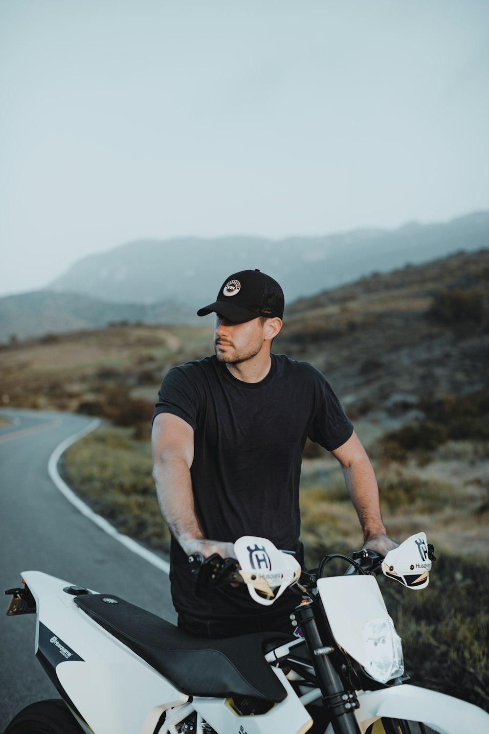 man in black crew neck t-shirt riding white and black bicycle on road during daytime