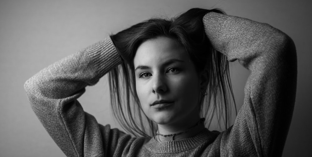 a black and white photo of a woman holding her hair