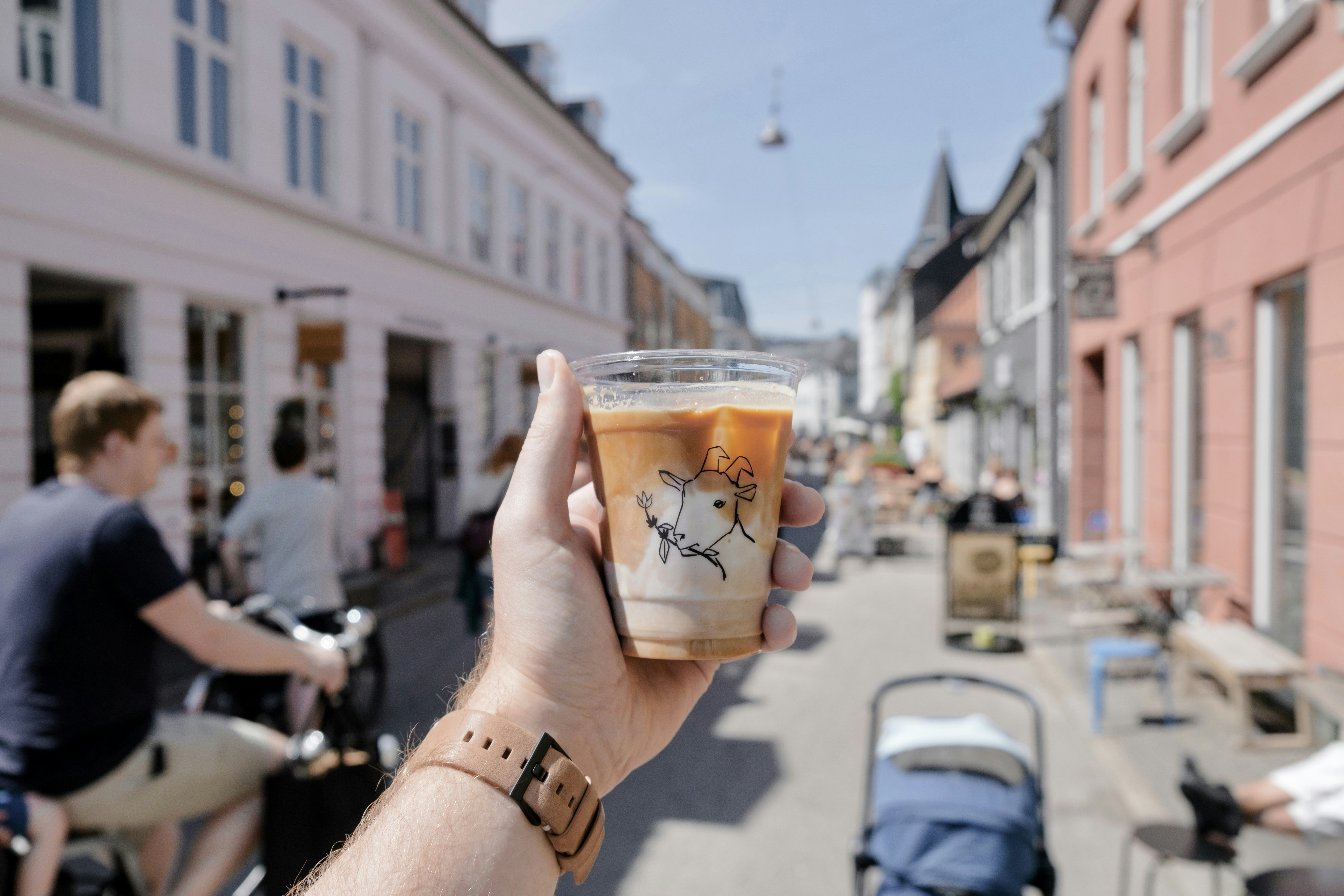 person holding clear glass cup with brown liquid, 