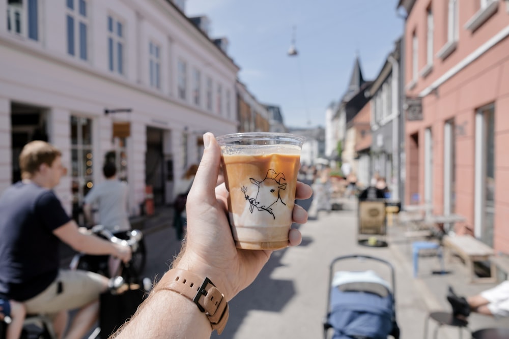 person holding clear glass cup with brown liquid