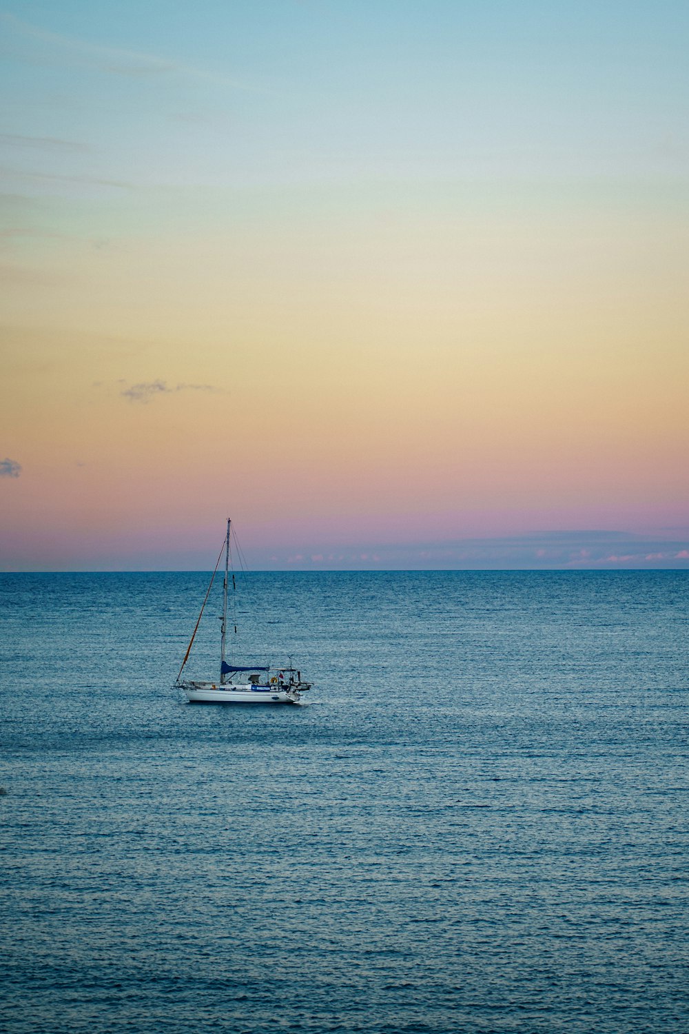 a sailboat in the middle of the ocean at sunset