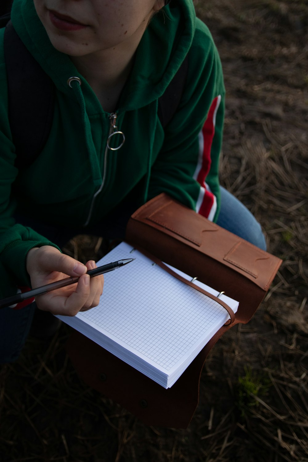 person in blue jacket holding pen and book