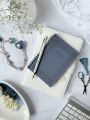 Elegant flat lay of wedding planning guides and a gold pen on a white marble surface.