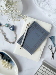 A flat lay of a white notebook with esoteric symbols and a black feather pen.