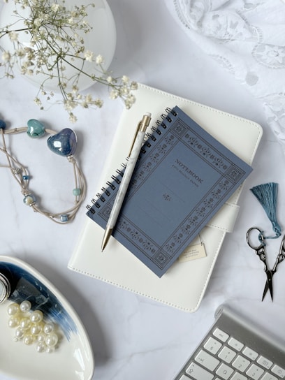 A serene flat lay of a royal blue journal, gold pen, and a vibrant adult coloring book open to a floral design.