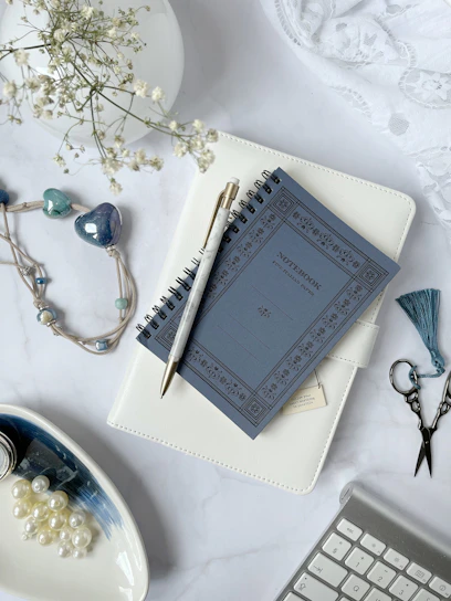 A neatly arranged flat lay of elegant planners with soft cream covers and delicate gold accents.