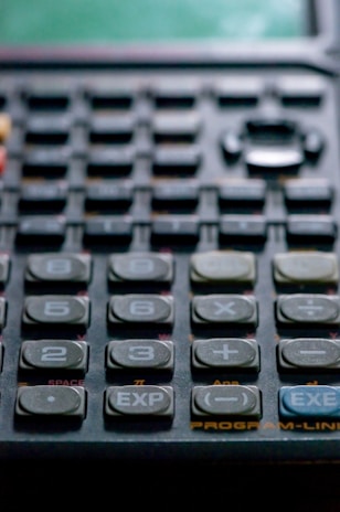 Close-up of a modern calculator with clear buttons and a bright display on a wooden table.