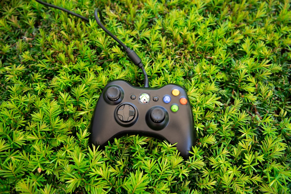 a video game controller laying on top of a lush green field