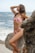 a woman in a bikini standing on a rock near the ocean